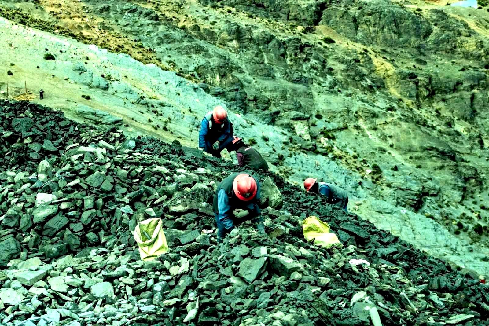 Aerial view of workers with helmets collecting stones in rocky quarry
