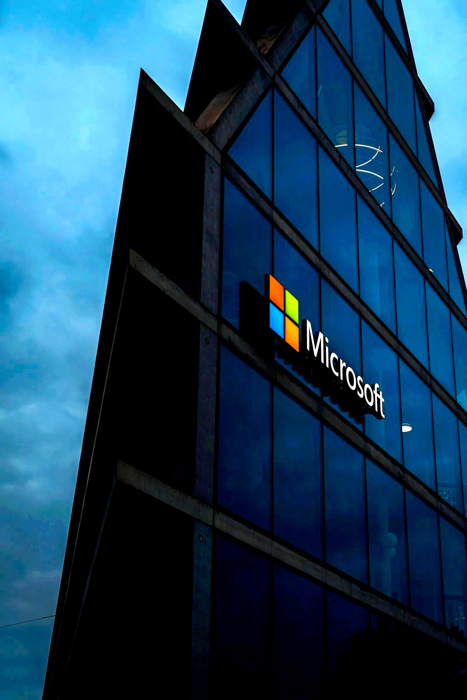 Modern glass-panel tech company campus building exterior against an evening sky