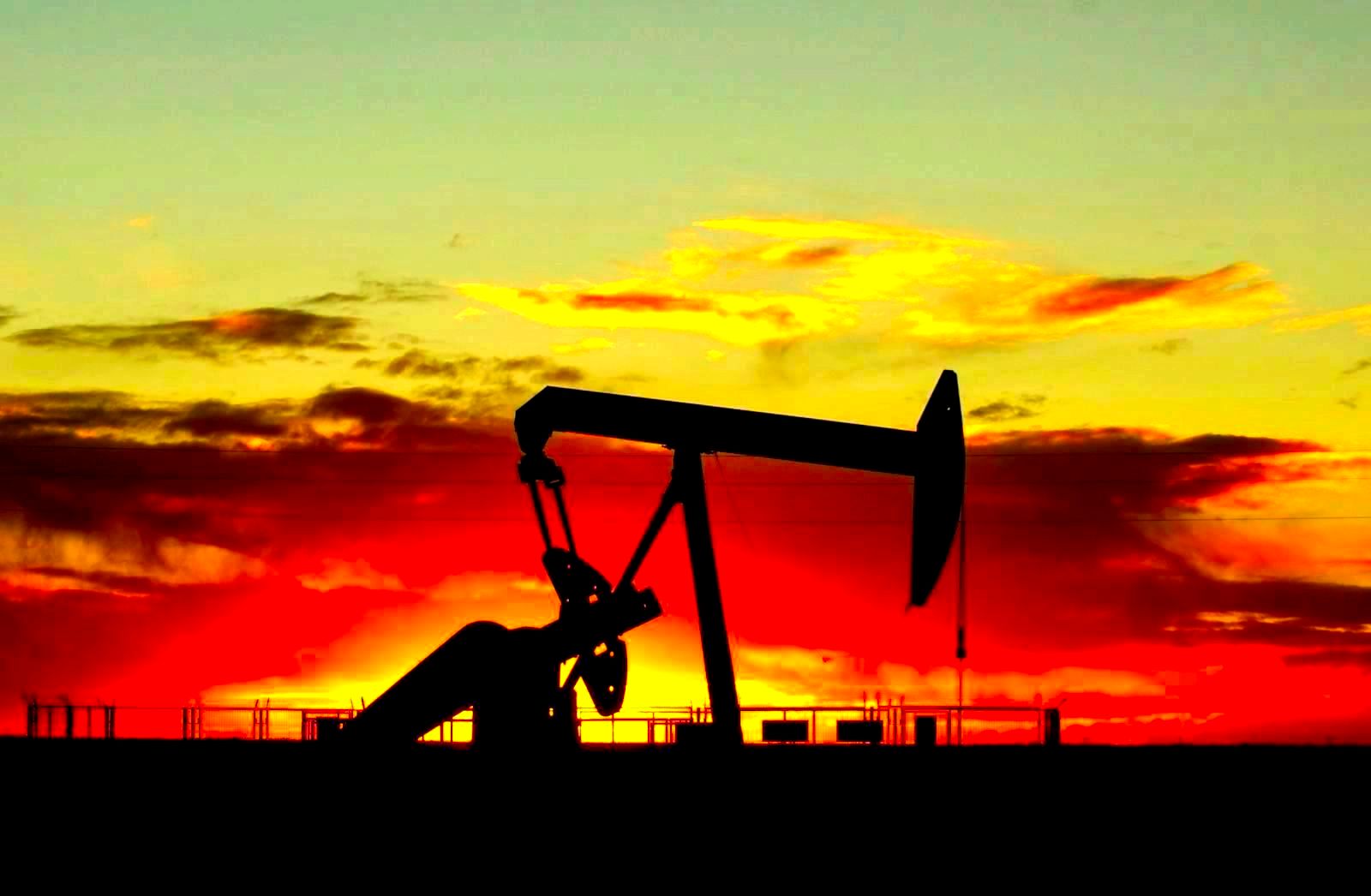 Oil pump jack silhouette against a dramatic sunset sky